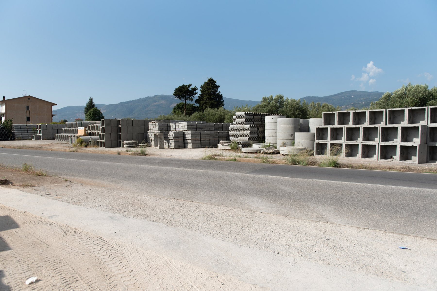 Piazzale dello stabilimento Adamo Pasqualino con manufatti in cemento e le montagne calabresi sullo sfondo
